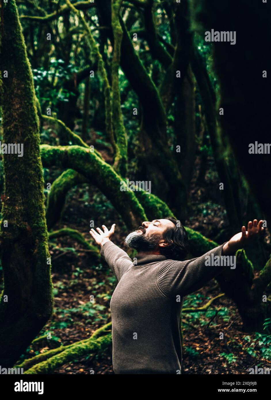 Adult man adventure standing in the forest and outstretching open arms for success and satisfaction emotion. Inner interior balance. Healthy lifestyle. Environment and climate change. Loving planet Stock Photo