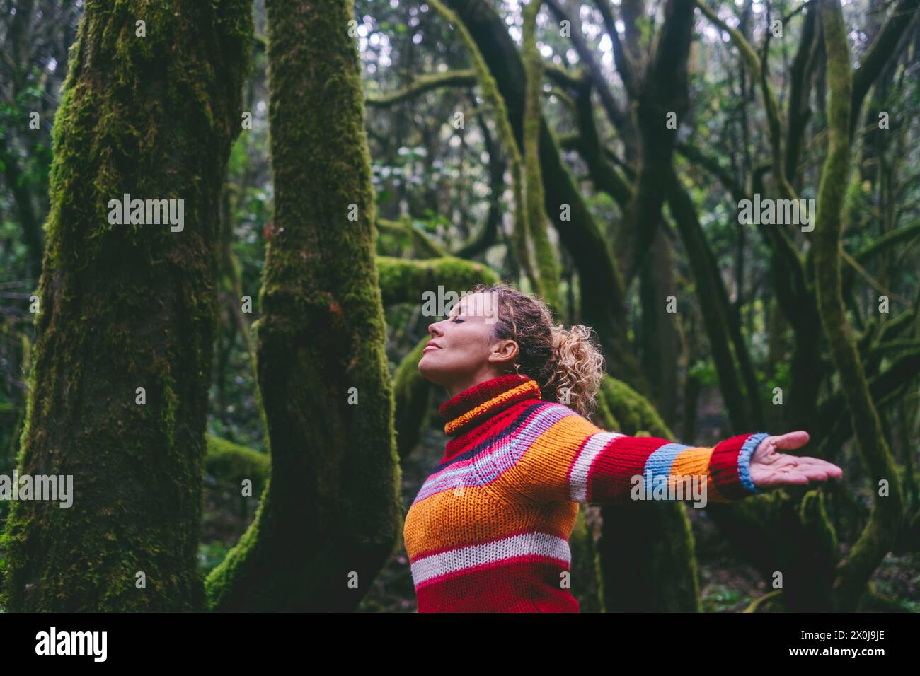 Side view of happy tourist enjoying green forest woods and trees opening arms and outstretching with smile expression and serene wellbeing. Healthy nature lifestyle people outdoors leisure adventure Stock Photo
