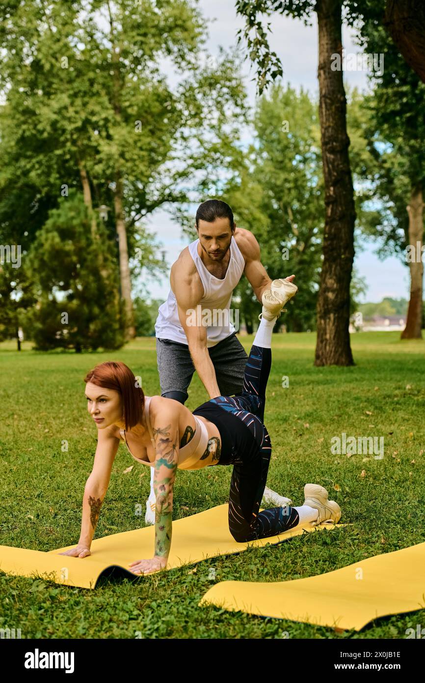 A woman in sportswear practice yoga together in a park with personal trainer, showcasing determination and motivation. Stock Photo