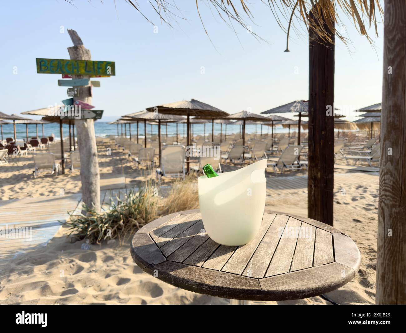An empty beer bottle in a plastic champagne cooler on the beach of Gouves on the vacation island of Crete Stock Photo