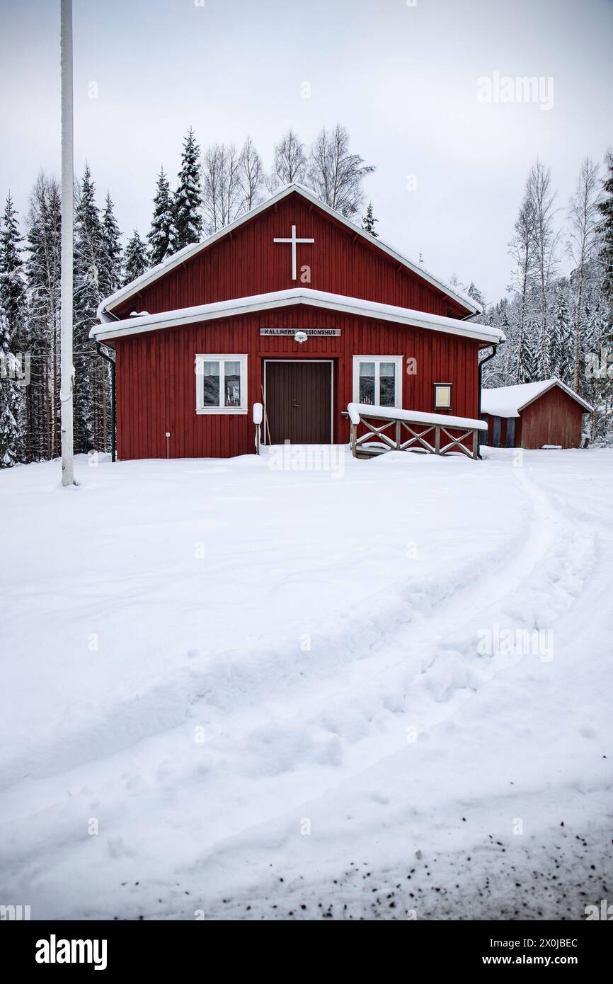 Typical red Swedish house. Wooden house in a winter landscape with ice and snow. Small settlement in the middle of a snowy forest. Landscape shot in Sweden Stock Photo
