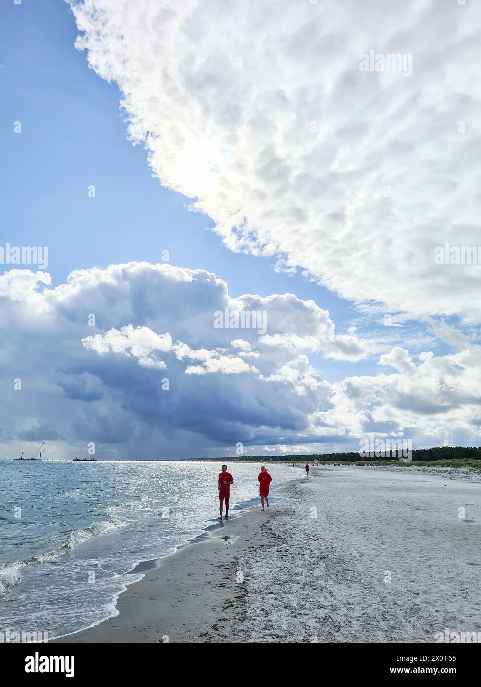 Two people walking along the water's edge on the beach in Prerow, Mecklenburg-Vorpommern, Germany Stock Photo