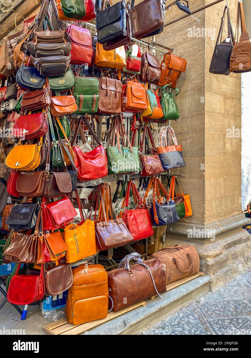 Florence, Italy - April 04, 2024: leather handbags and purses of Florentine craftsmanship displayed for sale in Porcellino market under 16th century l Stock Photo