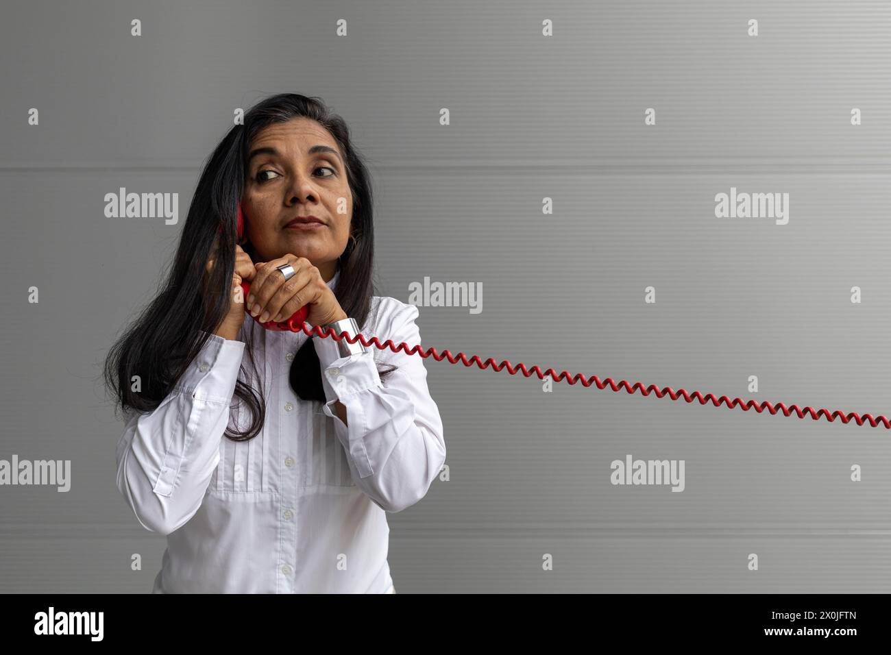 Latin American adult woman with a red headset posing on camera. Vintage technology concept Stock Photo