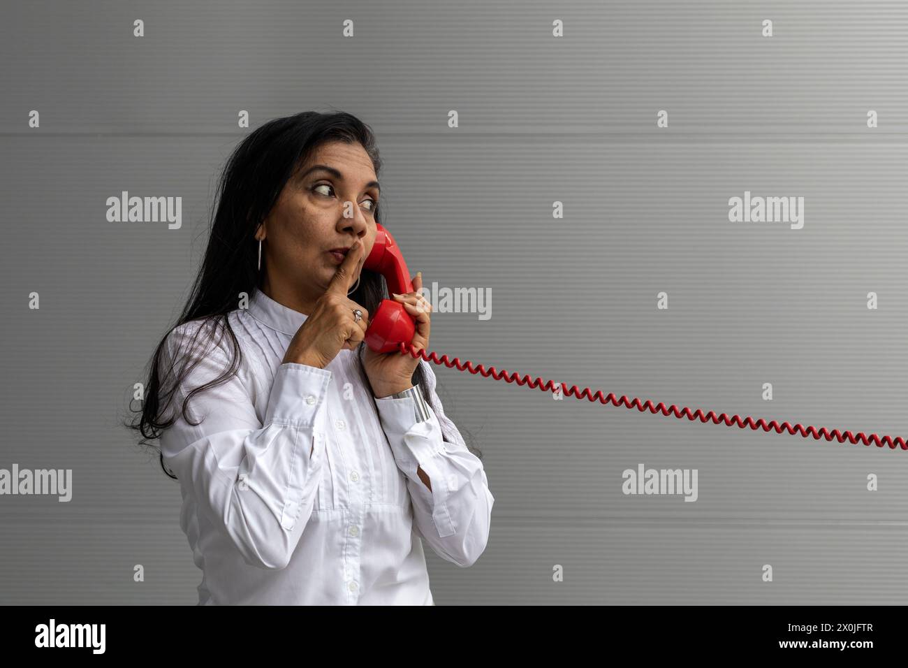 Latin American adult woman with a red headset posing on camera. Vintage technology concept Stock Photo