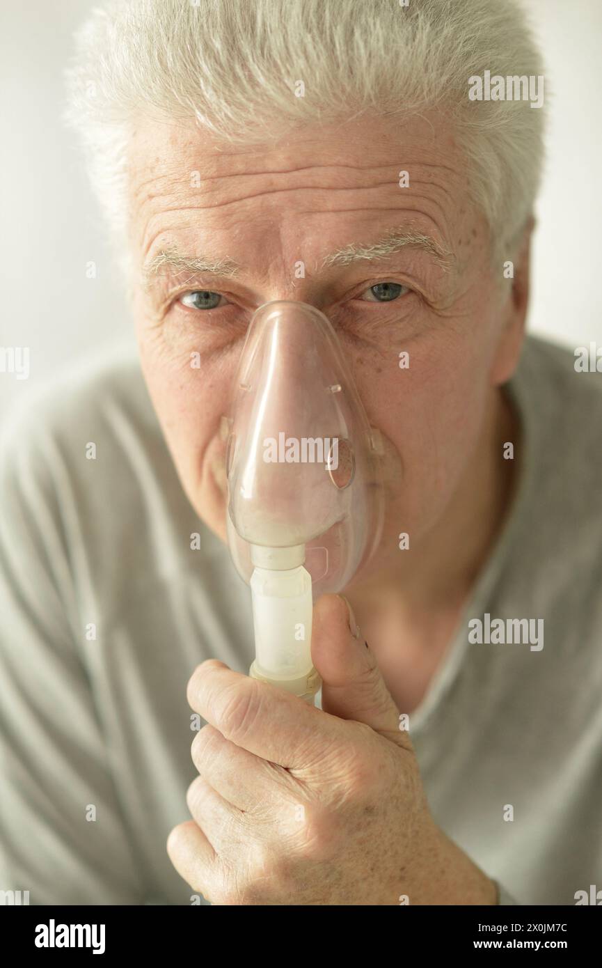 Close-up portrait of an elder man making inhalation Stock Photo