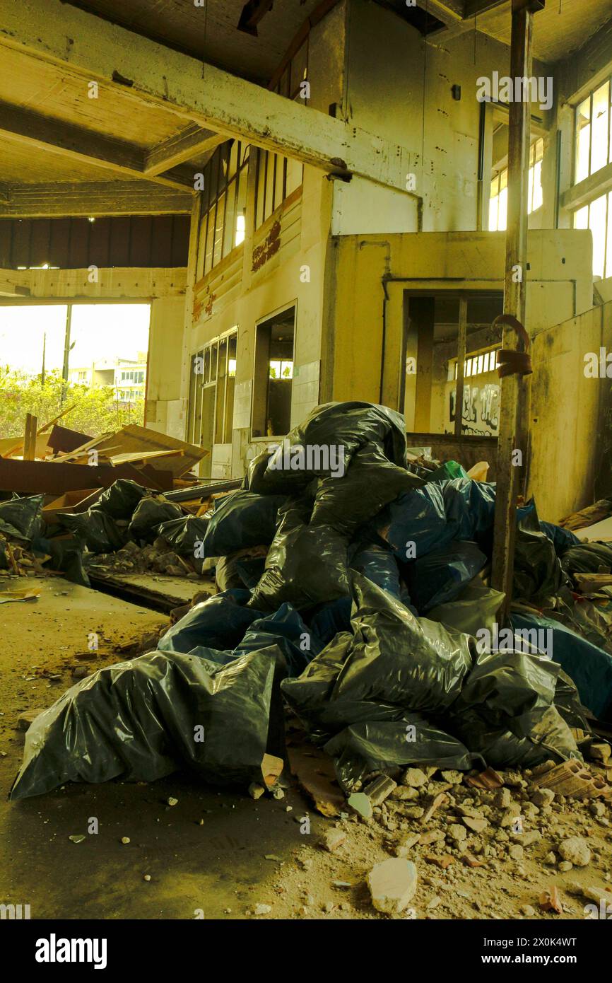 Peer into the gritty underbelly of urban life with this arresting image capturing piles of trash bags amidst the desolation of abandoned city streets. Stock Photo