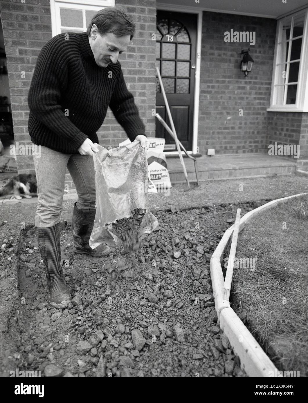 1980s, a man building a new driveway outside a house, putting down hard core rubble as a base. Hardcore is an essential material to lay strong foundations for any building works. Stock Photo