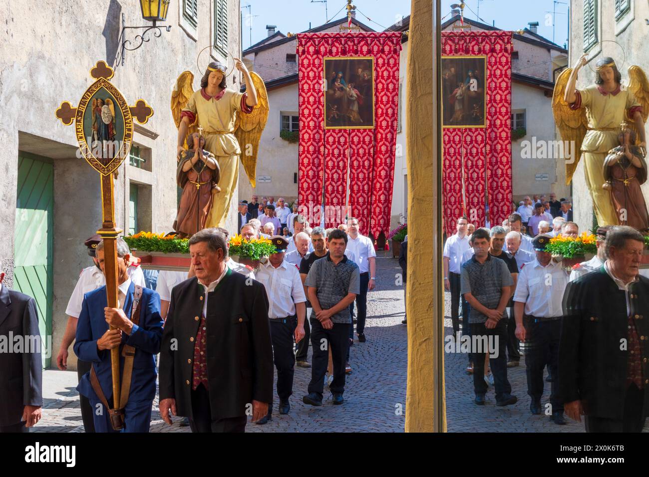 Tramin an der Weinstraße (Termeno sulla Strada del Vino), Corpus Christi procession, people in traditional clothes, church flags, reflection in window in South Tyrol, Trentino-South Tyrol, Italy Stock Photo