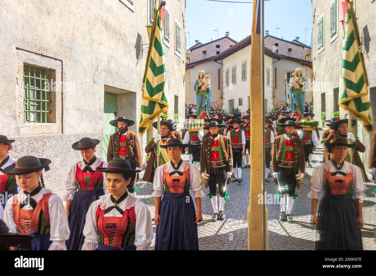 Tramin an der Weinstraße (Termeno sulla Strada del Vino), Corpus Christi procession, people in traditional clothes, church flags, reflection in window in South Tyrol, Trentino-South Tyrol, Italy Stock Photo