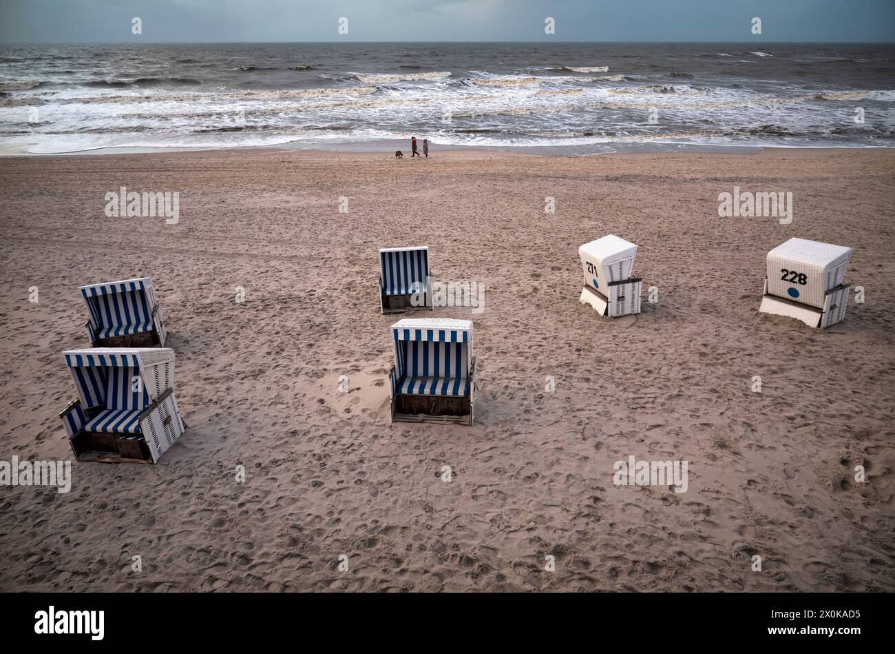 Empty beach chairs, sea, walker with dog, Rotes Kliff beach, Kampen, North Sea island of Sylt, North Frisia, Schleswig-Holstein, Germany Stock Photo