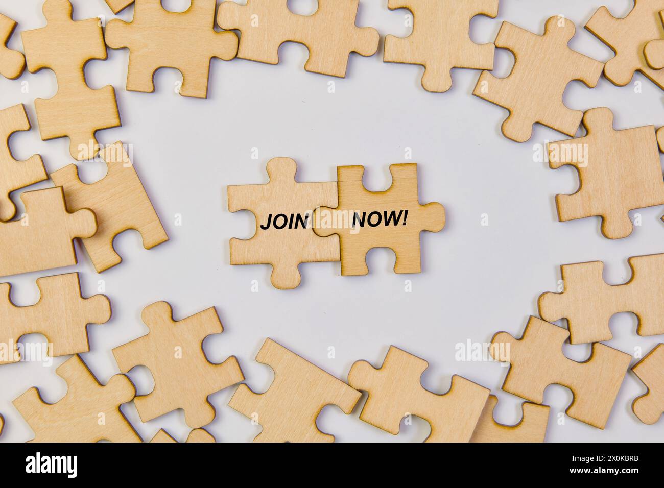 Compelling image featuring interlocking wooden puzzle pieces coming together to form a JOIN NOW inscription Stock Photo