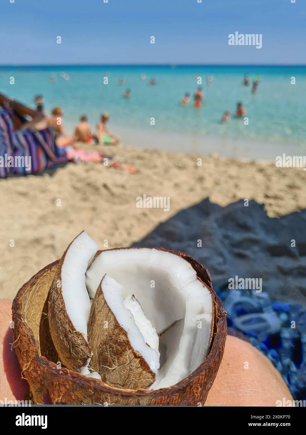 An open coconut with shell in the foreground, typical snack on the beach during a summer vacation in Mallorca, Spain Stock Photo