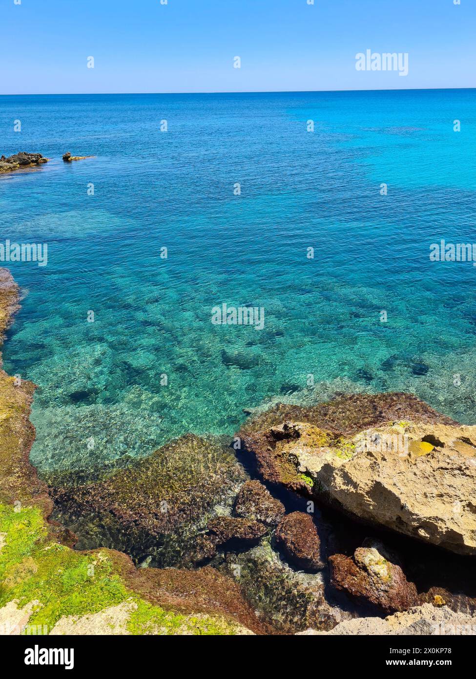 View over the rocks to the turquoise transparent water on the promenade of Cala Ratjada on a beautiful summer's day, Mallorca, Spain Stock Photo