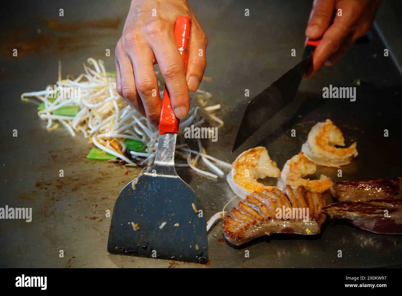 chef's hands with spatula over teppanyaki. cooking vegetables meat and
