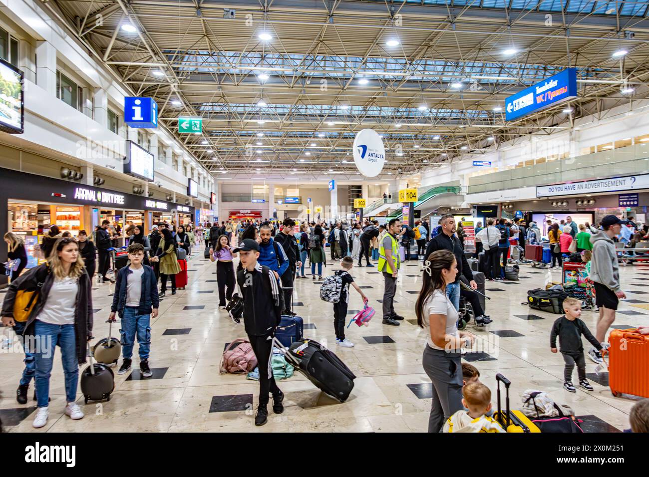 The baggage hall at Antalya Airport in Turkey, busy with passengers collecting their luggage Stock Photo