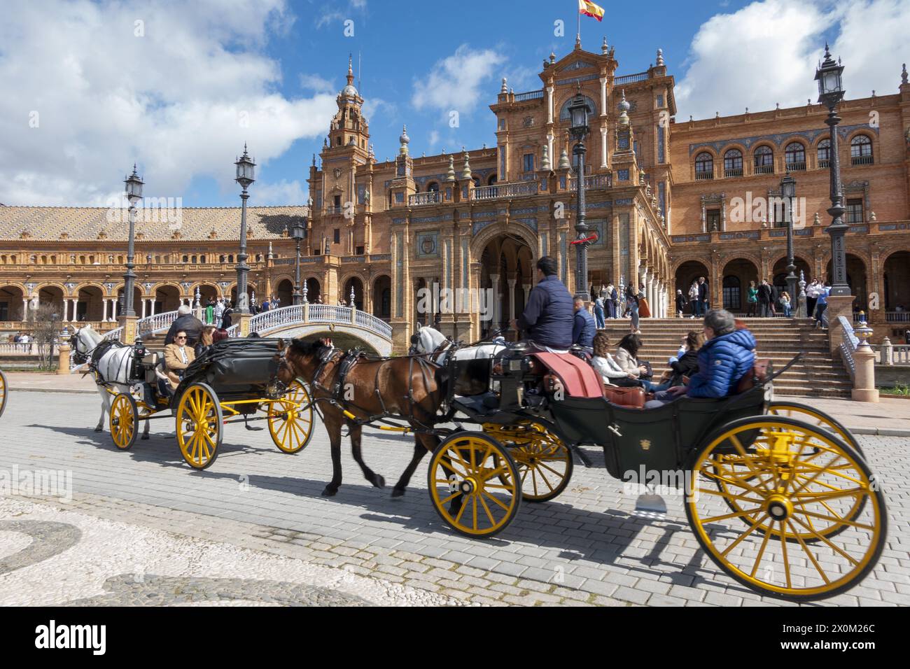 Seville, Spain - March 3, 2024: Horse-drawn carriages carrying tourists through the Plaza de España, in Seville Stock Photo
