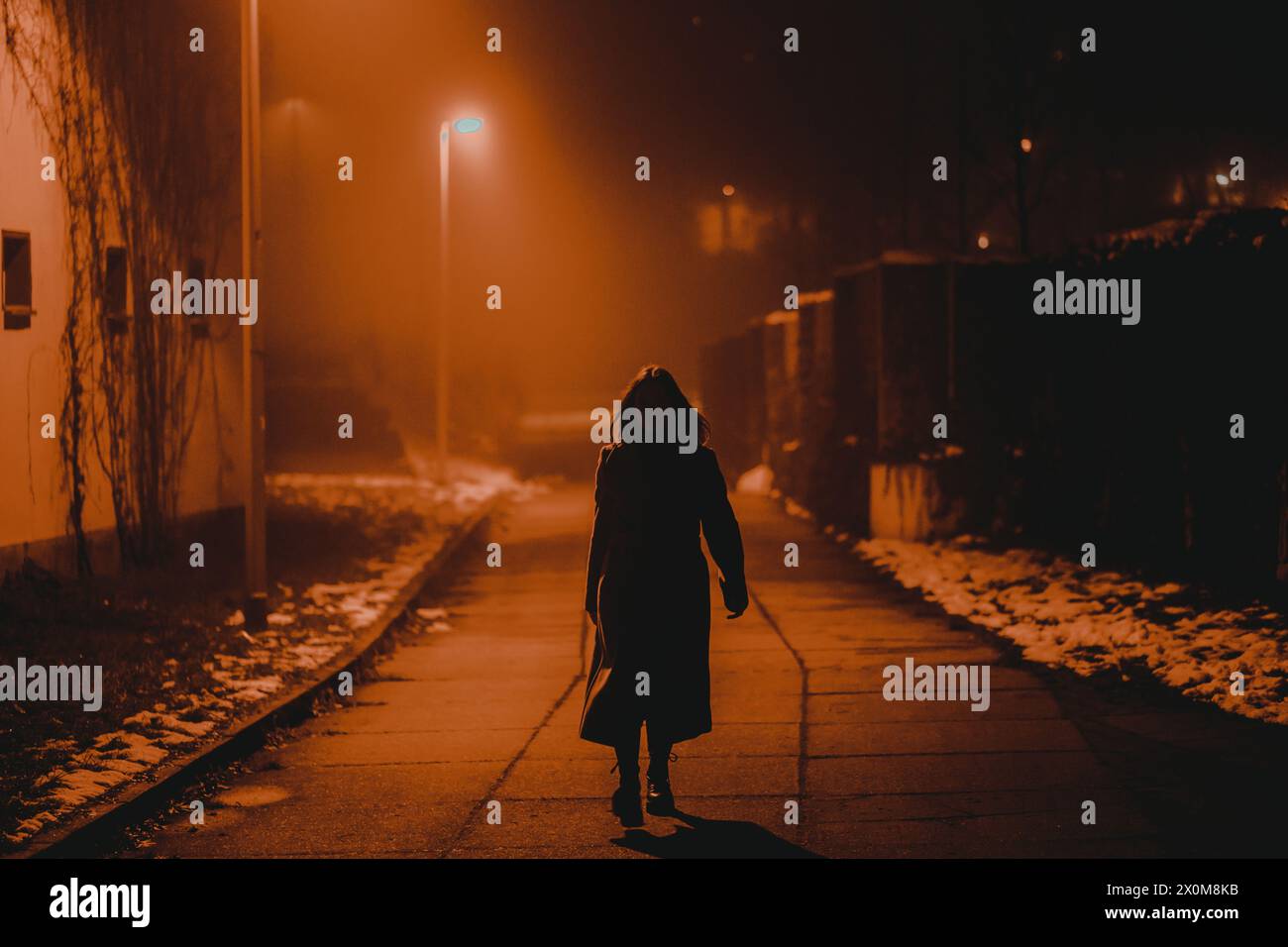 Silhouette of a young woman walking through a city at night. Stock Photo