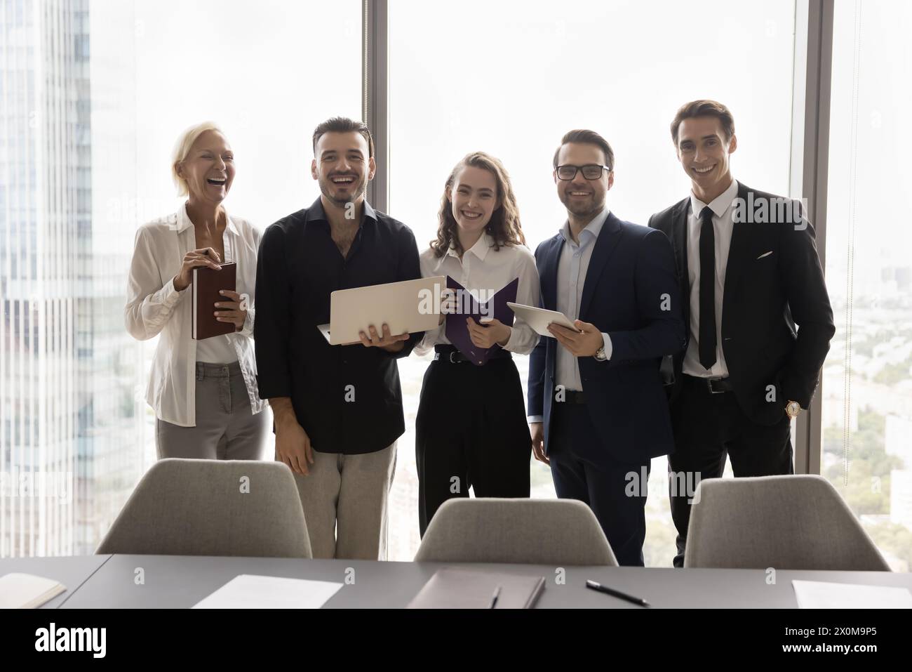 Teammates standing in row gathered in modern conference room Stock Photo