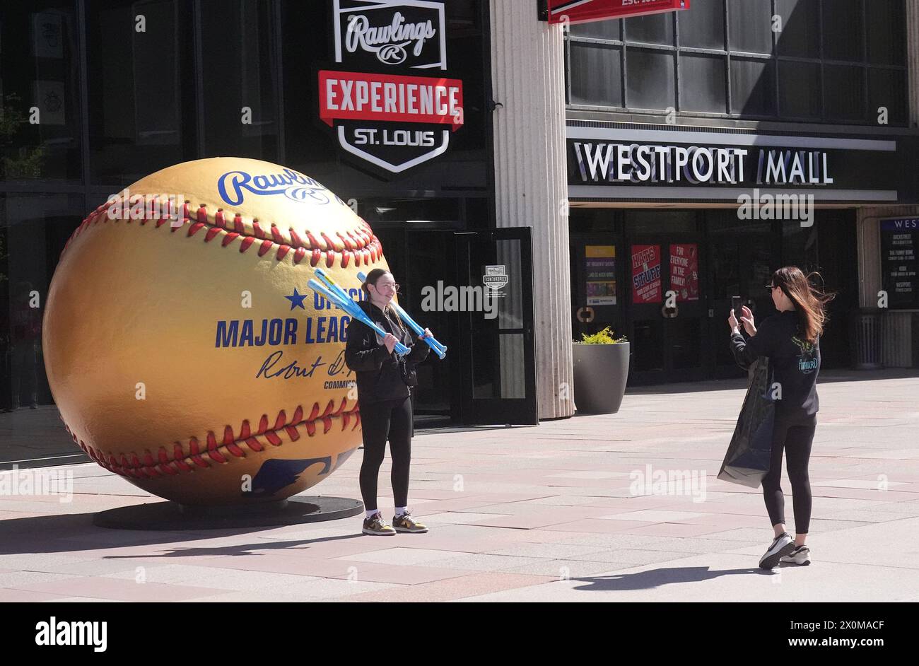 Maryland Heights, United States. 12th Apr, 2024. Visitors to the Rawlings Experience Store opening make their photo in front of a large Rawlings Gold ball in Westport Plaza in Maryland Heights, Missouri on Friday, April 12, 2024. The store is the first store for Rawlings, with bats, balls and gloves plus a display of those who have won Gold Glove Awards since 1958. The award is bestowed on some of the game's greatest defensive players. Photo by Bill Greenblatt/UPI Credit: UPI/Alamy Live News Stock Photo