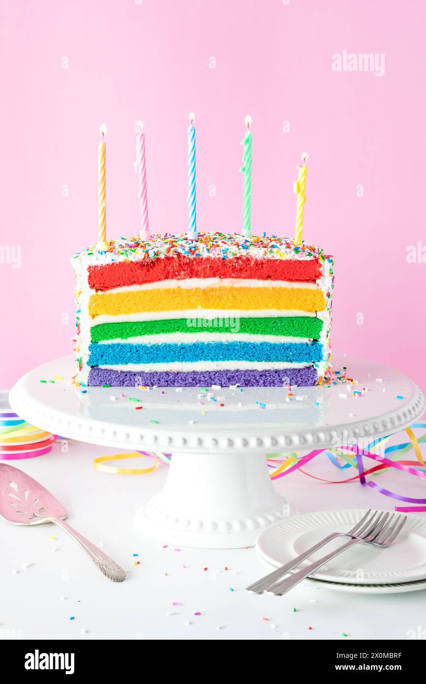A rainbow birthday cake with lit candles ready to be blown out Stock ...