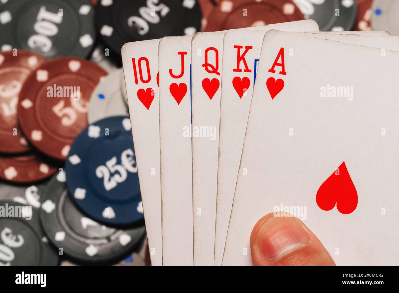 Royal flush in poker in the hands of the player on the background of gaming chips in the casino closeup Stock Photo