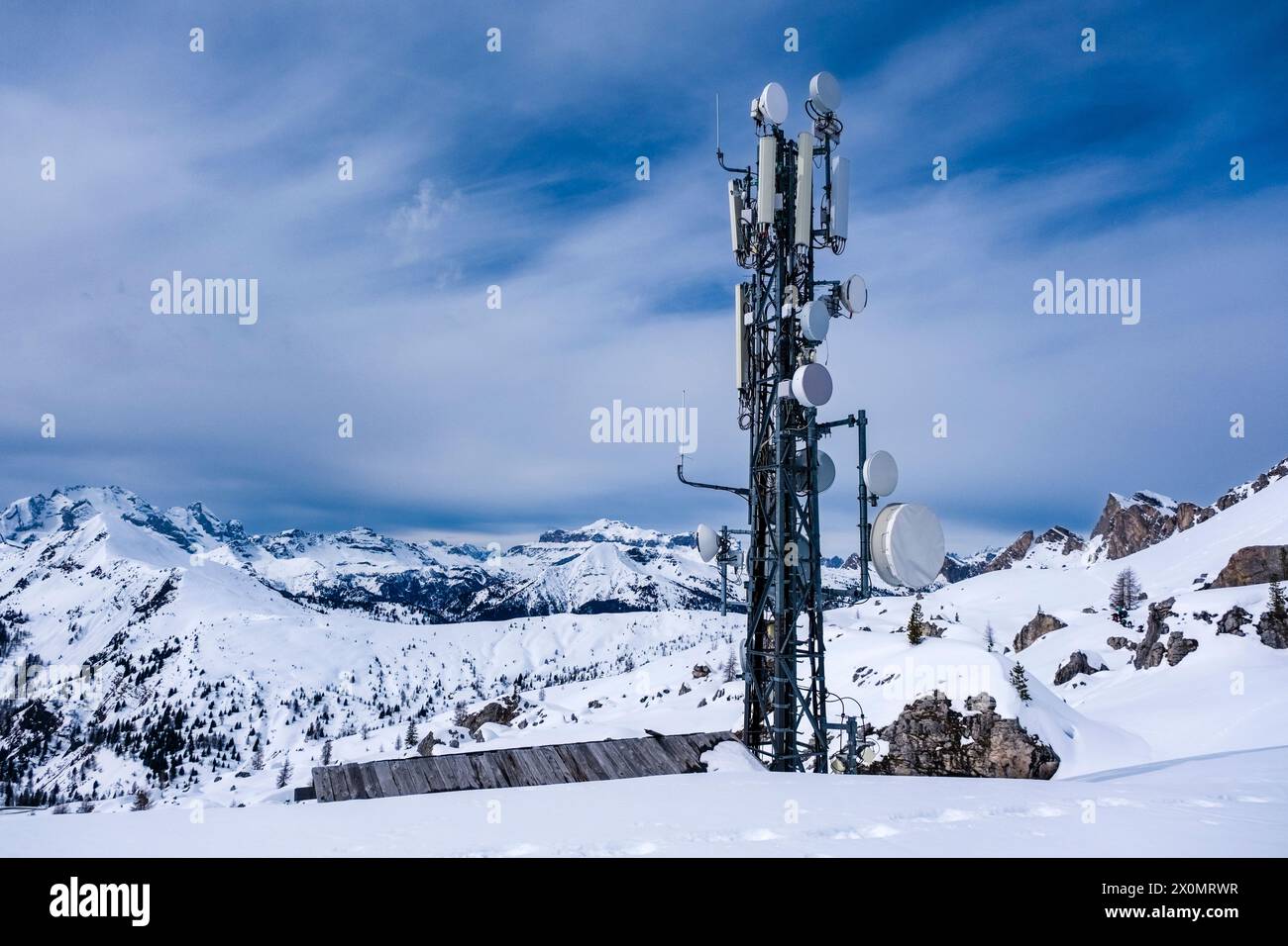 Snow-covered slopes of alpine Dolomite landscape with a telecommunications station above Giau pass in winter. Stock Photo