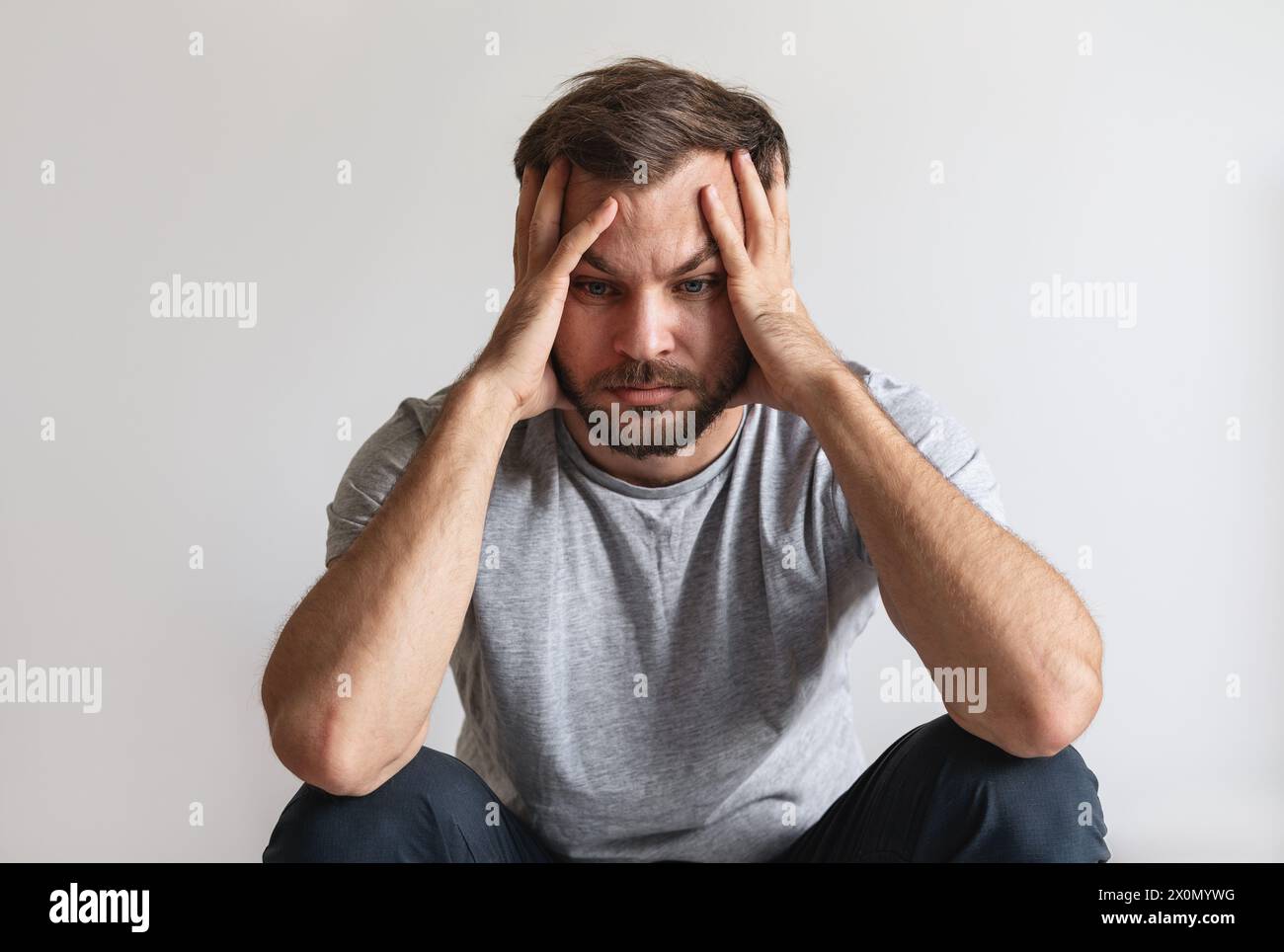 Male mental illness concept. Tired unhappy man holds head with hands. Melancholy and downcast person. Stock Photo
