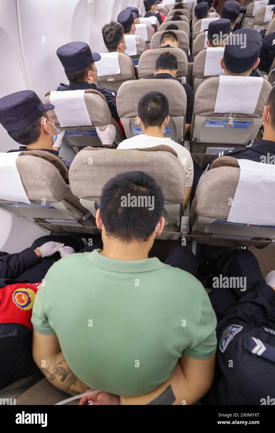 Wuhan, China. 13th Apr, 2024. Gambling and scam suspects escorted by Chinese police officers are pictured on a chartered flight to China, April 13, 2024. Two police-chartered civilian flights brought back 130 gambling and scam suspects from Cambodia earlier on Saturday. This marks the first lot of suspects repatriated from Cambodia this year as Chinese and Cambodian police launched joint operations to crack down on crimes associated with gambling and swindling. Credit: Yin Gang/Xinhua/Alamy Live News Stock Photo