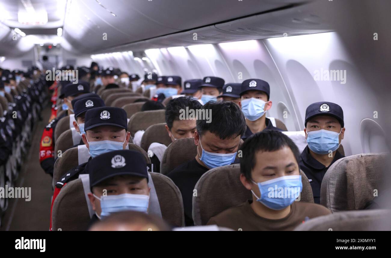 Wuhan, China. 13th Apr, 2024. Gambling and scam suspects escorted by Chinese police officers are pictured on a chartered flight to China, April 13, 2024. Two police-chartered civilian flights brought back 130 gambling and scam suspects from Cambodia earlier on Saturday. This marks the first lot of suspects repatriated from Cambodia this year as Chinese and Cambodian police launched joint operations to crack down on crimes associated with gambling and swindling. Credit: Yin Gang/Xinhua/Alamy Live News Stock Photo