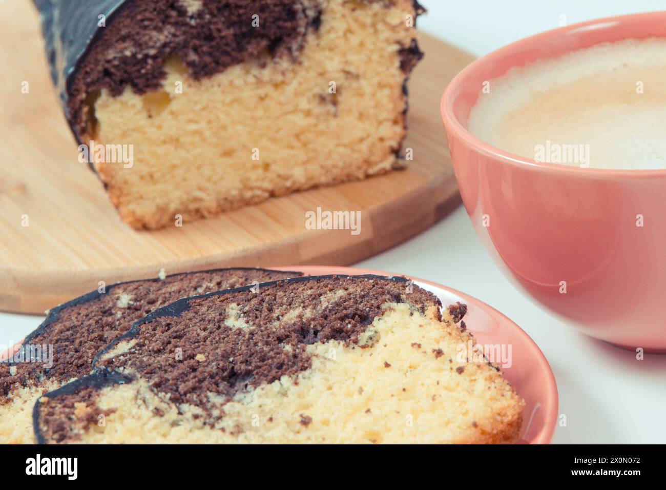 Fresh baked pieces of yeast dough with cocoa and chocolate icing, cup of coffee with milk. Delicious dessert Stock Photo