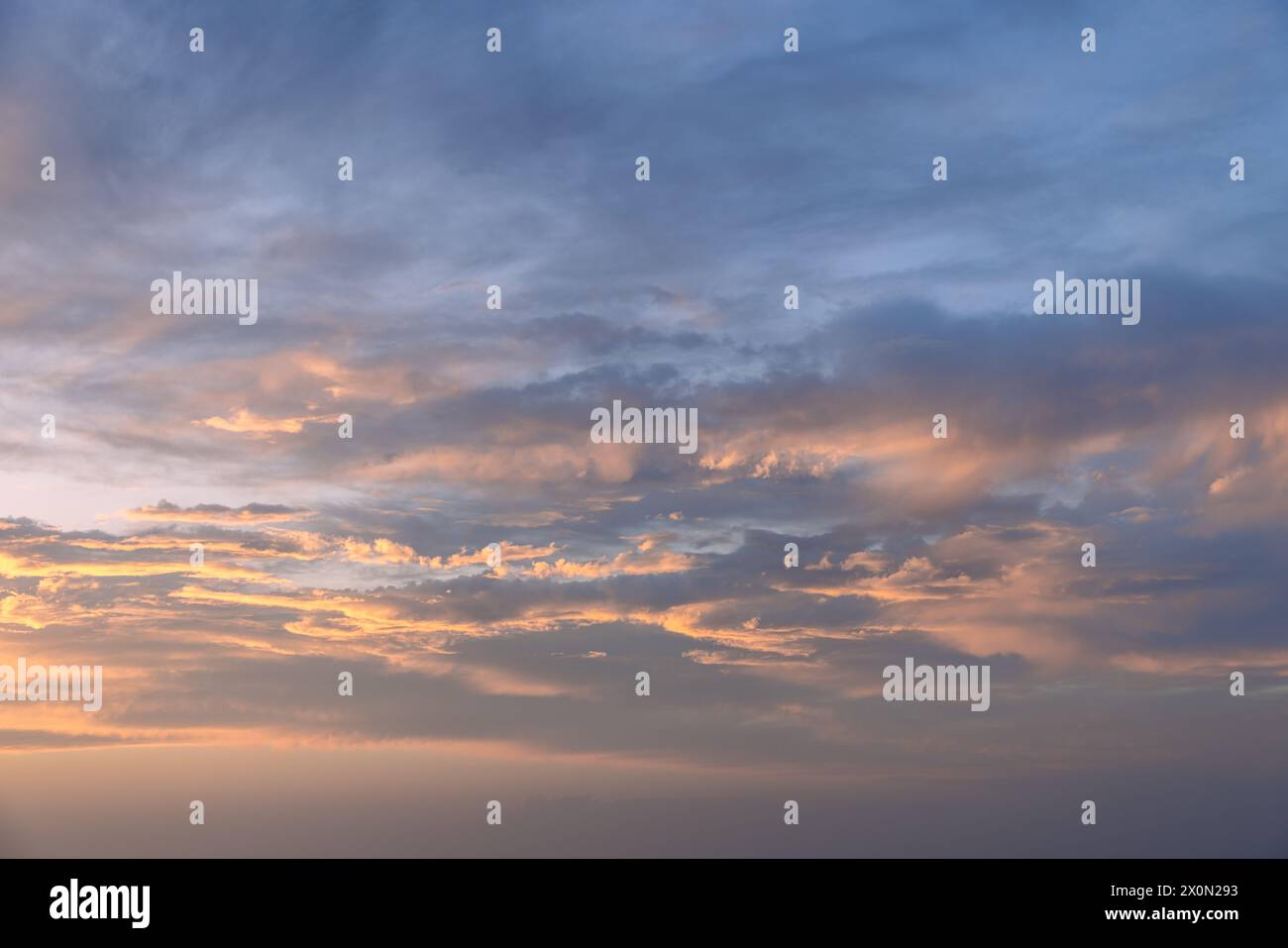 The evening sky, aglow with peach and blue gradients, offers a peaceful ambiance, ideal for backgrounds in artistic projects or sky replacements Stock Photo