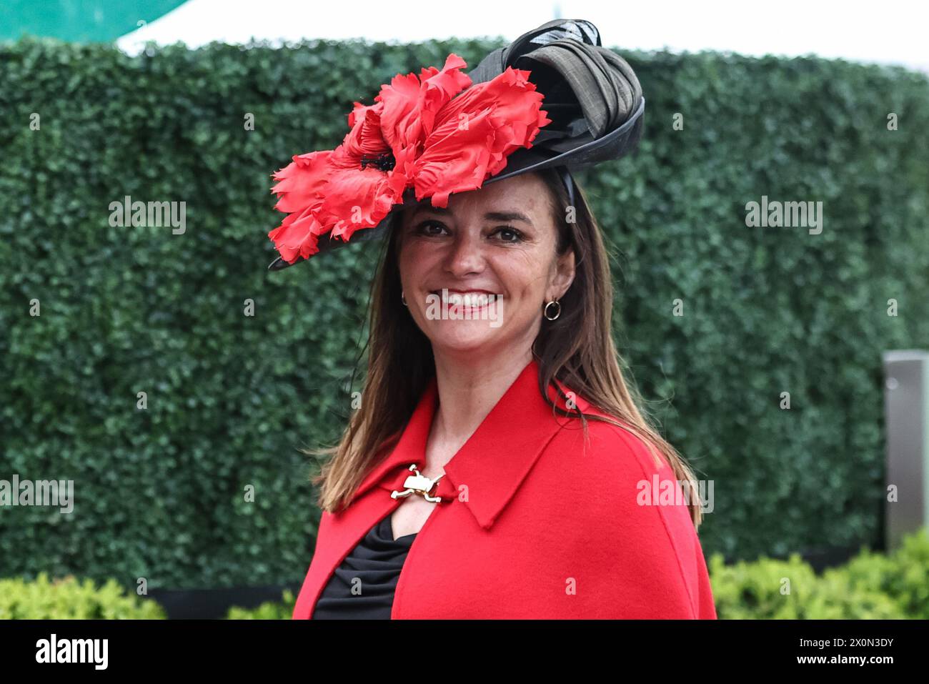 A racegoervwearing a red dress and a black hat with a big red flower