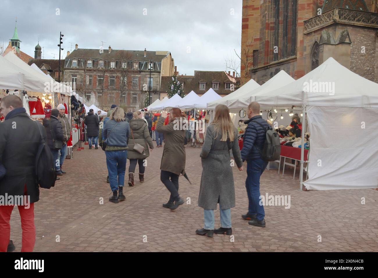 Colmar, France - December 21, 2023: People are walking near Christmas market and  St. Martin church Stock Photo