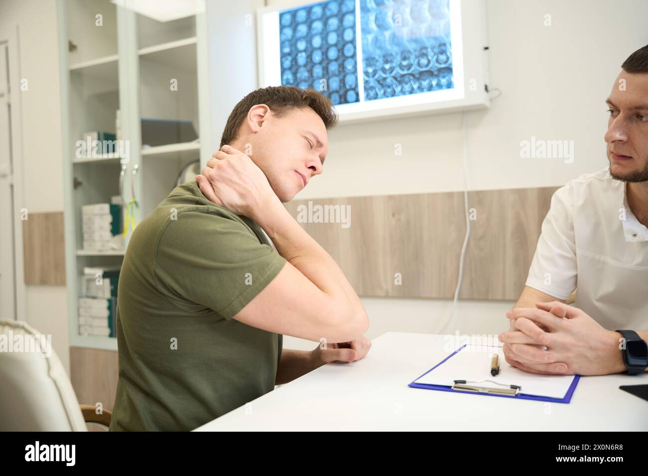 Man complaining of cervicalgia to medical professional Stock Photo