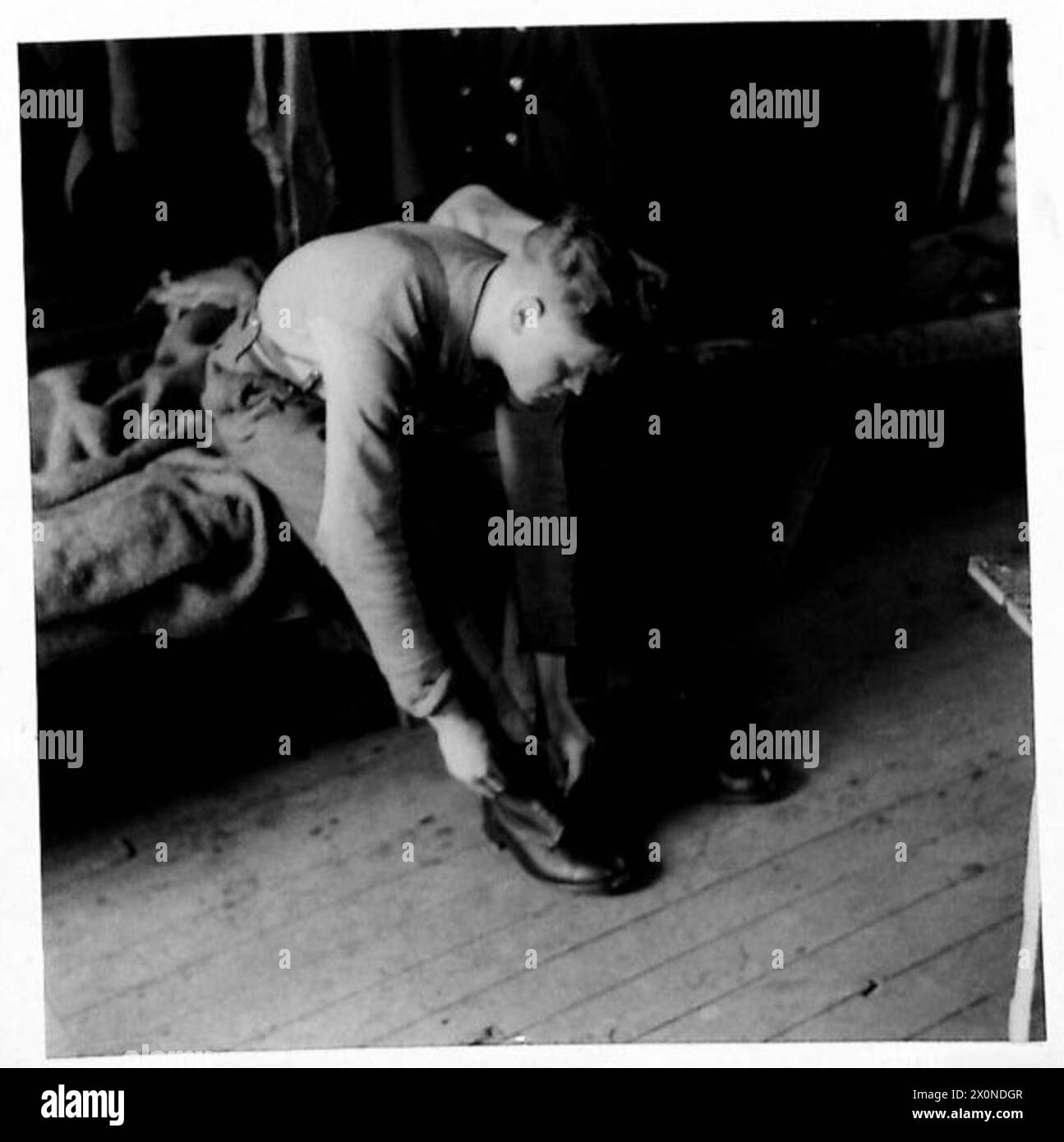 A DAY WITH A GUNNER IN THE ORKNEYS - At the sound of reveille our gunner dresses and prepares to leave his Nissen hut. Photographic negative , British Army Stock Photo