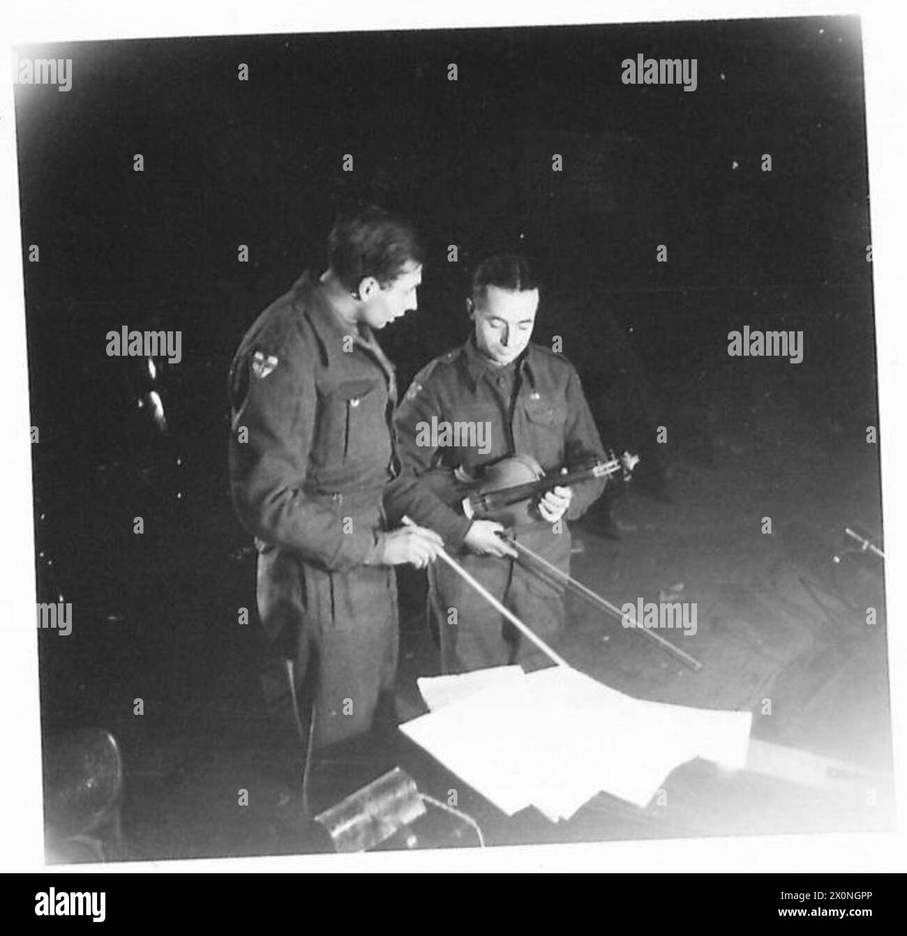 EIGHTH ARMY - The conductor of the orchestra goes over the score with the leader of the violins. Conductor - Dennis Sabin, 99 Salcott Road, Battersea, S.W.11. The Leader - Patrick McGrory 81, Hirstwood Road, Saltaire, Shipley, Yorks. Photographic negative , British Army Stock Photo