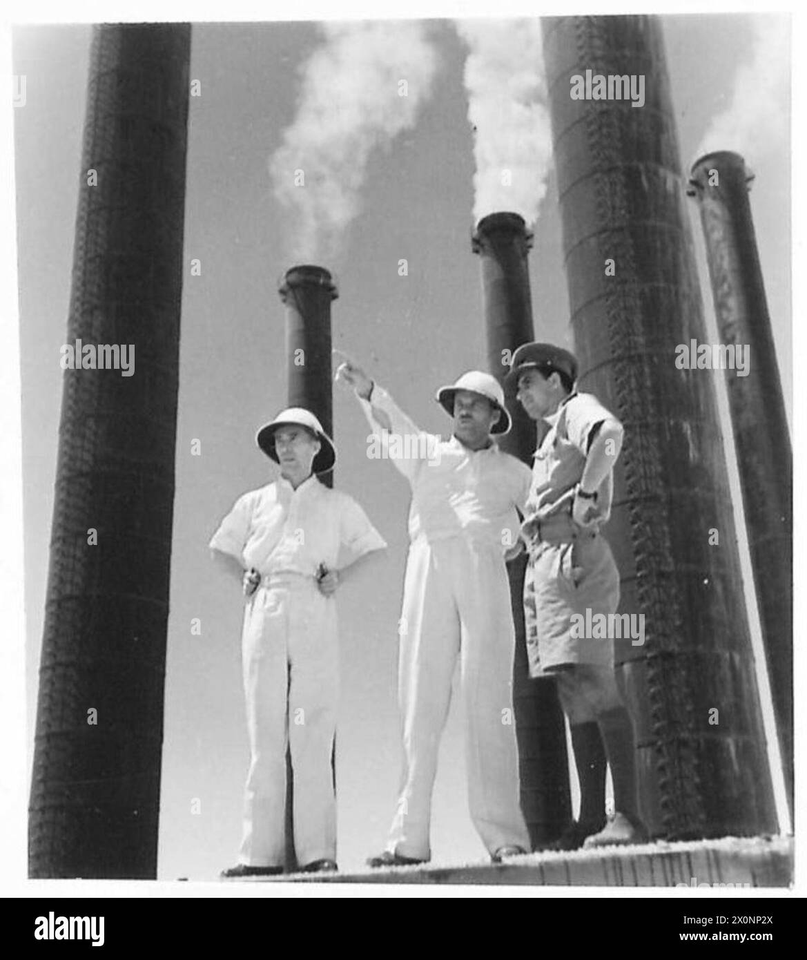 PICTURES FROM IRAN (PERSIA) - Officials of the Anglo-Iranian Oil Company pointing out details to a British officer. Seen in the background are the chimneys of the giant oil refinery at full blast, 24 hours after we had captured it. Photographic negative , British Army Stock Photo