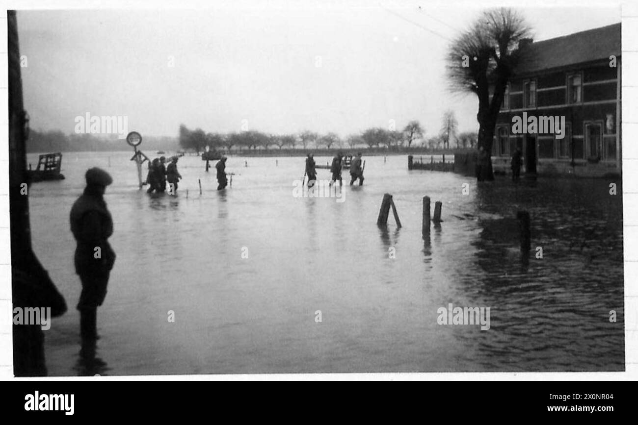 THE MAAS IN FLOOD NEAR MAESEYK - Sappers of the Royal Engineers wade through the floods on the river banks, as they make their way to dinner. Photographic negative , British Army, 21st Army Group Stock Photo