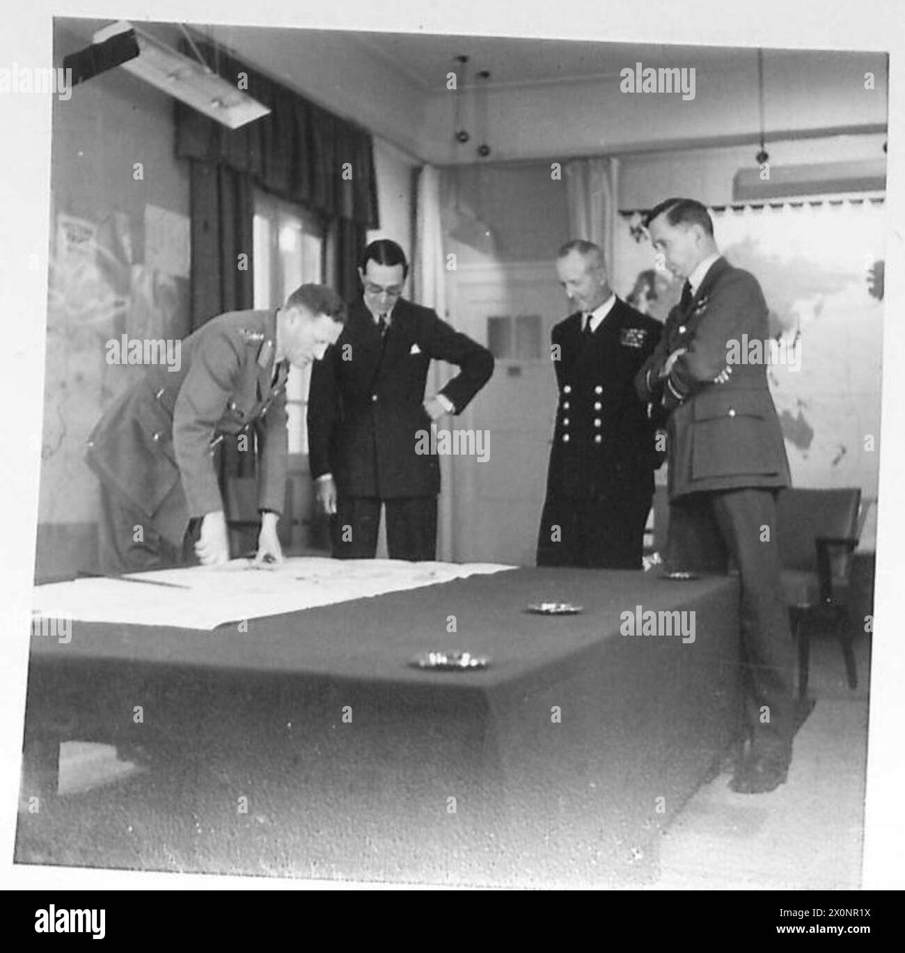 CONFERENCE OF THE THREE M.E. SERVICE CHIEFS - General Sir Claude Auchinleck, the C-in-C with Sir Walter Monckton (acting Minister of State), Admiral sir Andrew Cunningham (Mediterranean Fleet) and Air Marshal Sir A. Tedder. The C-in-C is pointing to a map. Photographic negative , British Army Stock Photo