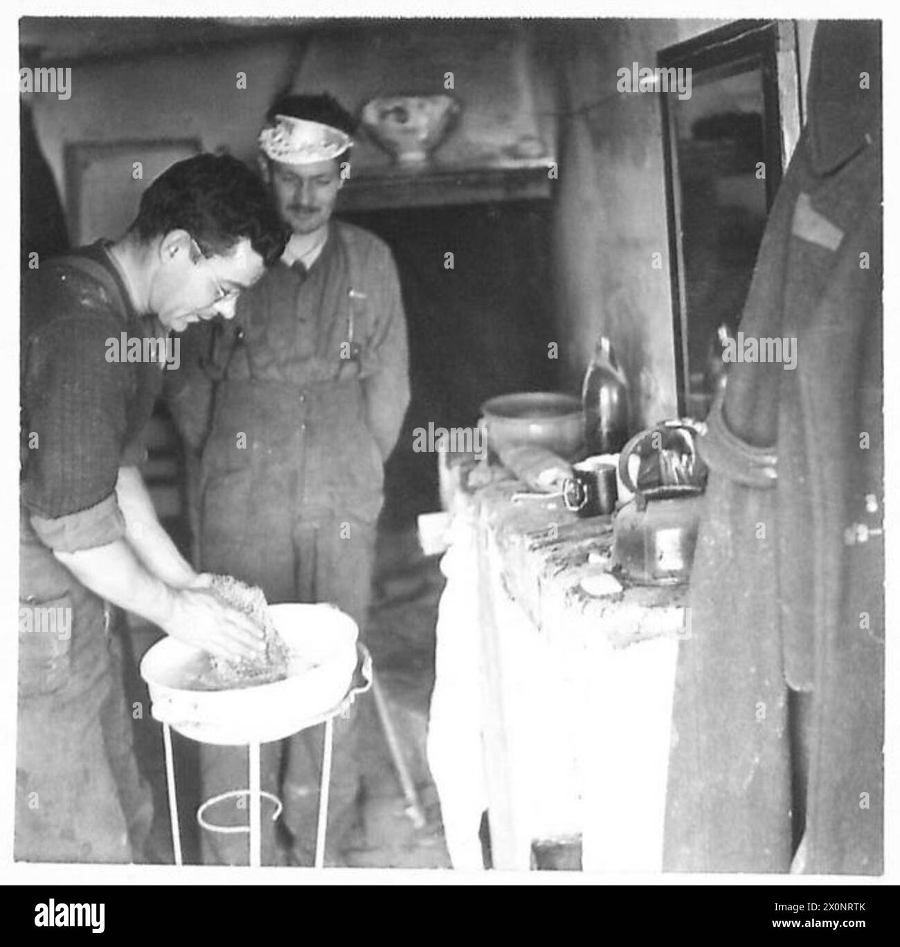 ITALY : EIGHTH ARMYFRONT LINE VILLAGE - Pte. G.R. Paulley of 55 Castle Avenue, Winipeg, washing clothing in his billet. Wearing a makeshift 'crown' is L/Cpl. Routledge of 582 Delaware Avenue, Toronto. Photographic negative , British Army Stock Photo