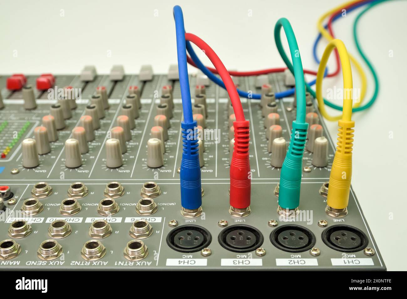 Music mixing console with connected audio jack plugs. Different colors