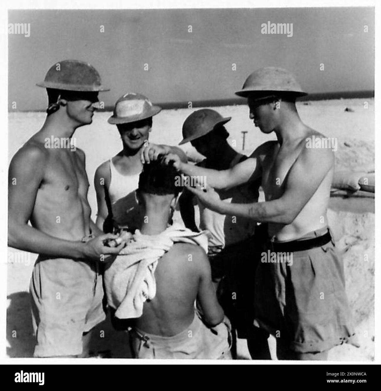 Soldiers observe a barber performing shaving duties during British Army ...