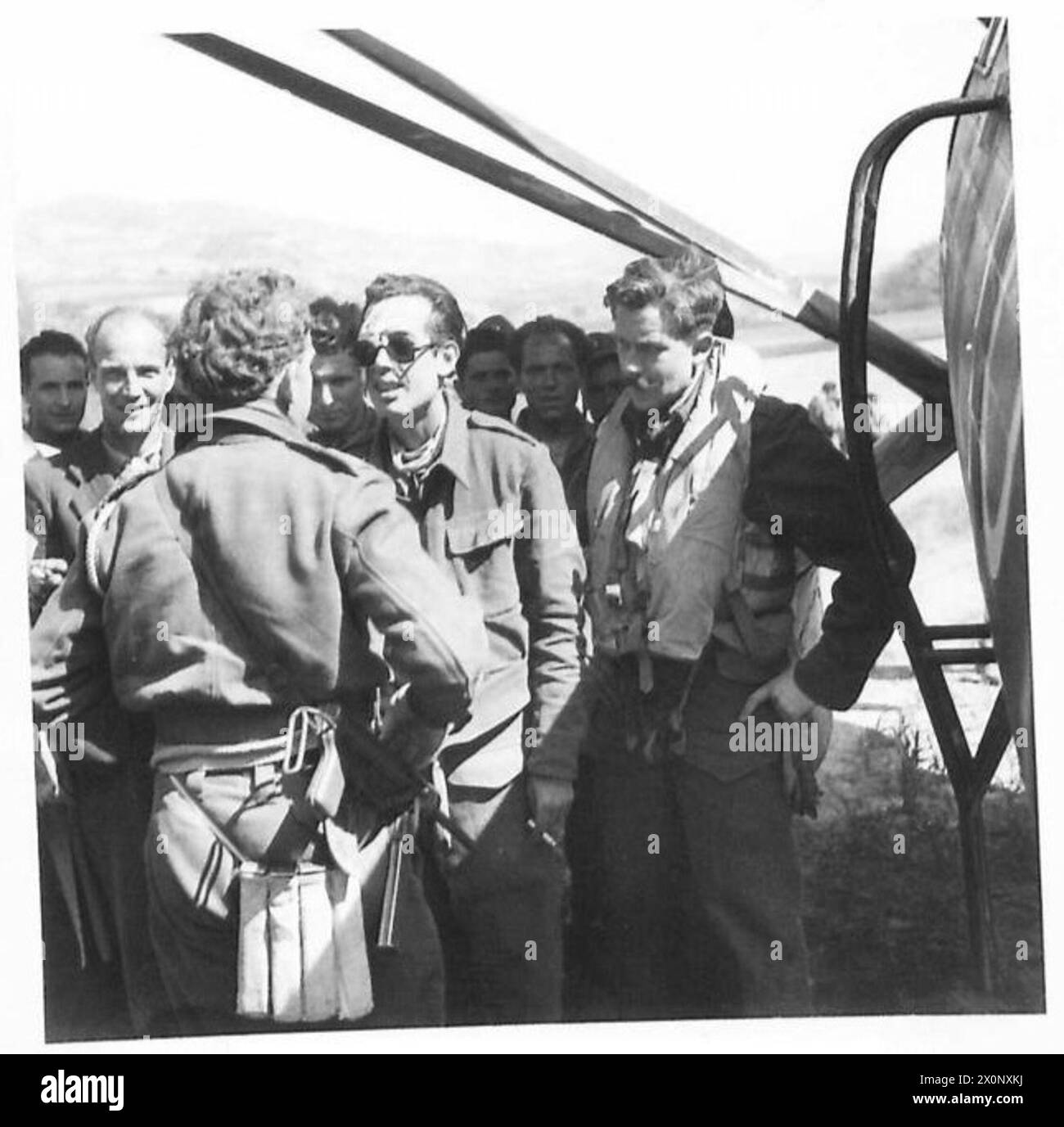 CUNEO-ALBA area, ITALY - A British liaison officer (left) talks to a wounded Partisan who is about to be evacuated on the Lysander. On the right is the pilot of the plane. Photographic negative , British Army Stock Photo