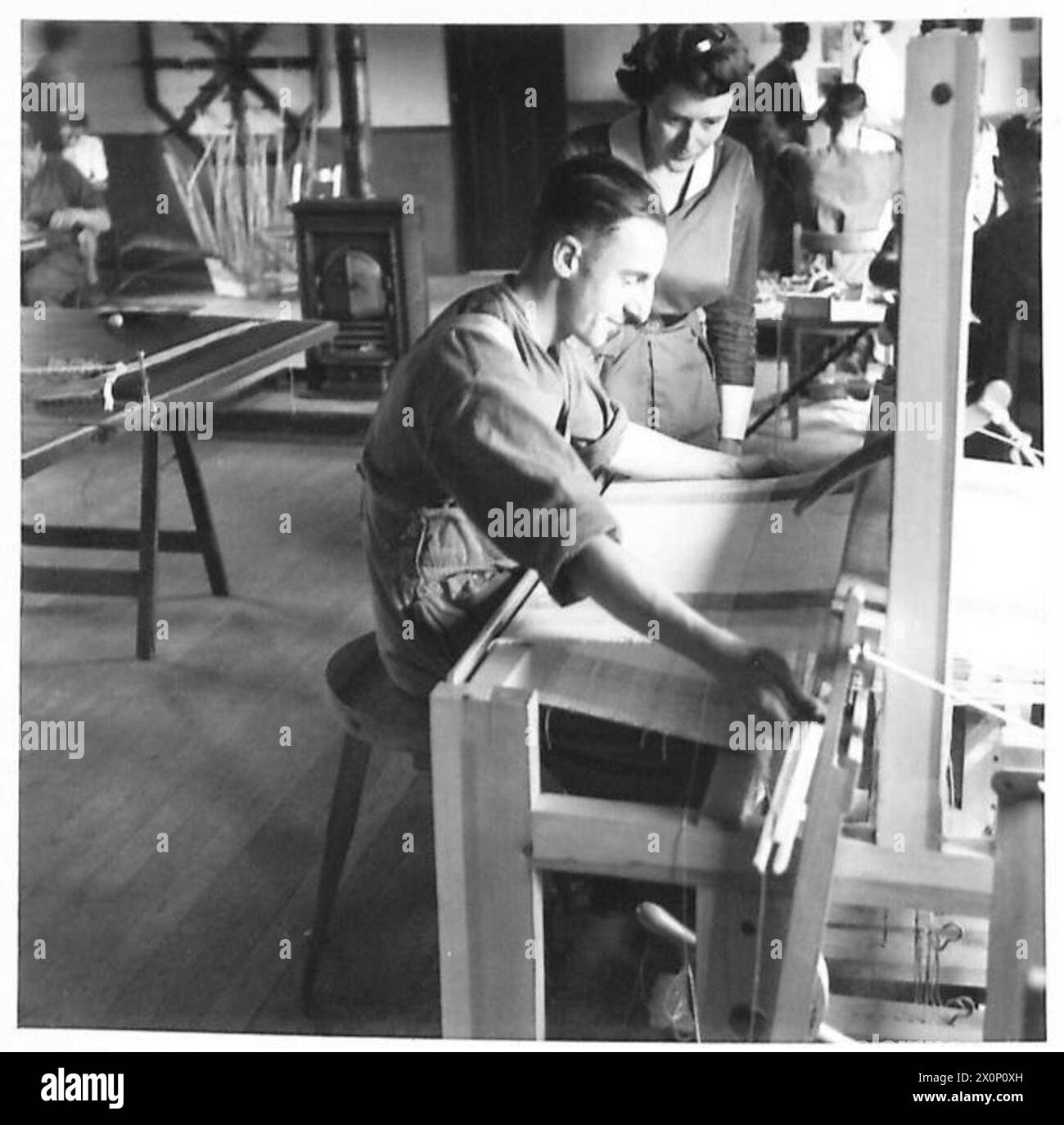 OCCUPATIONAL THERAPY CENTRE - A patient receiving instruction in the use of a foot power loom. Here the 'Harness' is raised by foot pedals, and a wide sweeping movement is necessary for the arms in passing the shuttle. This is good exercise for patients who experience difficulty in straightening their arms. Photographic negative , British Army Stock Photo