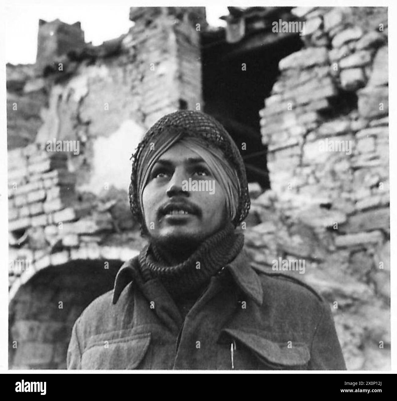 Soldier Bahadur Singh and other Indian troops wear camouflage nets over turbans instead of steel helmets in an Eighth Army front line village in Italy. Stock Photo