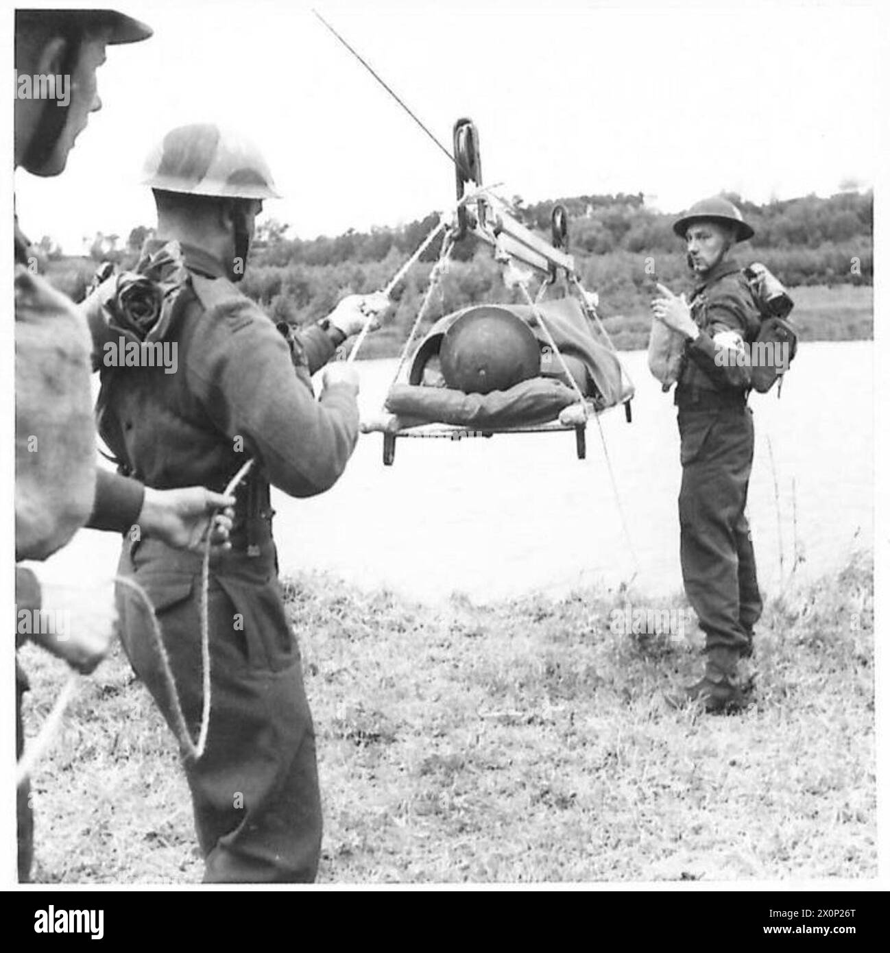 Soldiers use a pulley system to transfer casualties over a river, waiting for the signal to release the rope. Stock Photo