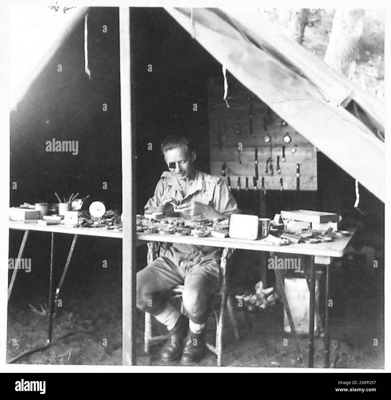 CONVALESCENT HOME IN NORTH AFRICA - Pte. F.G. Austine, 10 Royal Berkshire Regiment, of 41 Grenville Road, Hornsey Rise, Upper Holloway, N.19. Pte. Austine is the camp's watchmaker, who despite a crippled right hand caused by a shell splinter in Sicily, carried on his intricate work with skill. Photographic negative , British Army Stock Photo