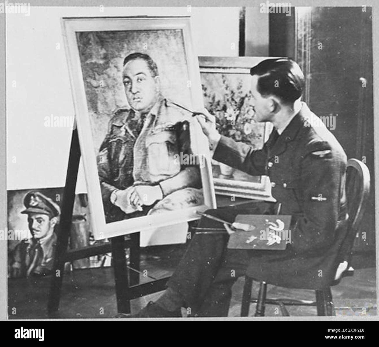 R.A.F. STATION HAS ITS OWN ARTIST - When he can spare the time, the Station commander of a Halifax Bomber station, in Yorkshire, sits for his portrait - and the artist is Leading Aircraftman Thomas G.Hill of lngleside, Park Lane, Sandbach, Cheshire. Leading Aircraftman Hill is one of the flight mechanics on the station. Before he joined the R.A.F. in 1940 he was a designer and artist for an important Manchester textile firm. He had been to an art school and attended secondary school art classes and had shown his pictures in many art exhibitions. Picture (issued 1944) shows - Leading Aircraftma Stock Photo