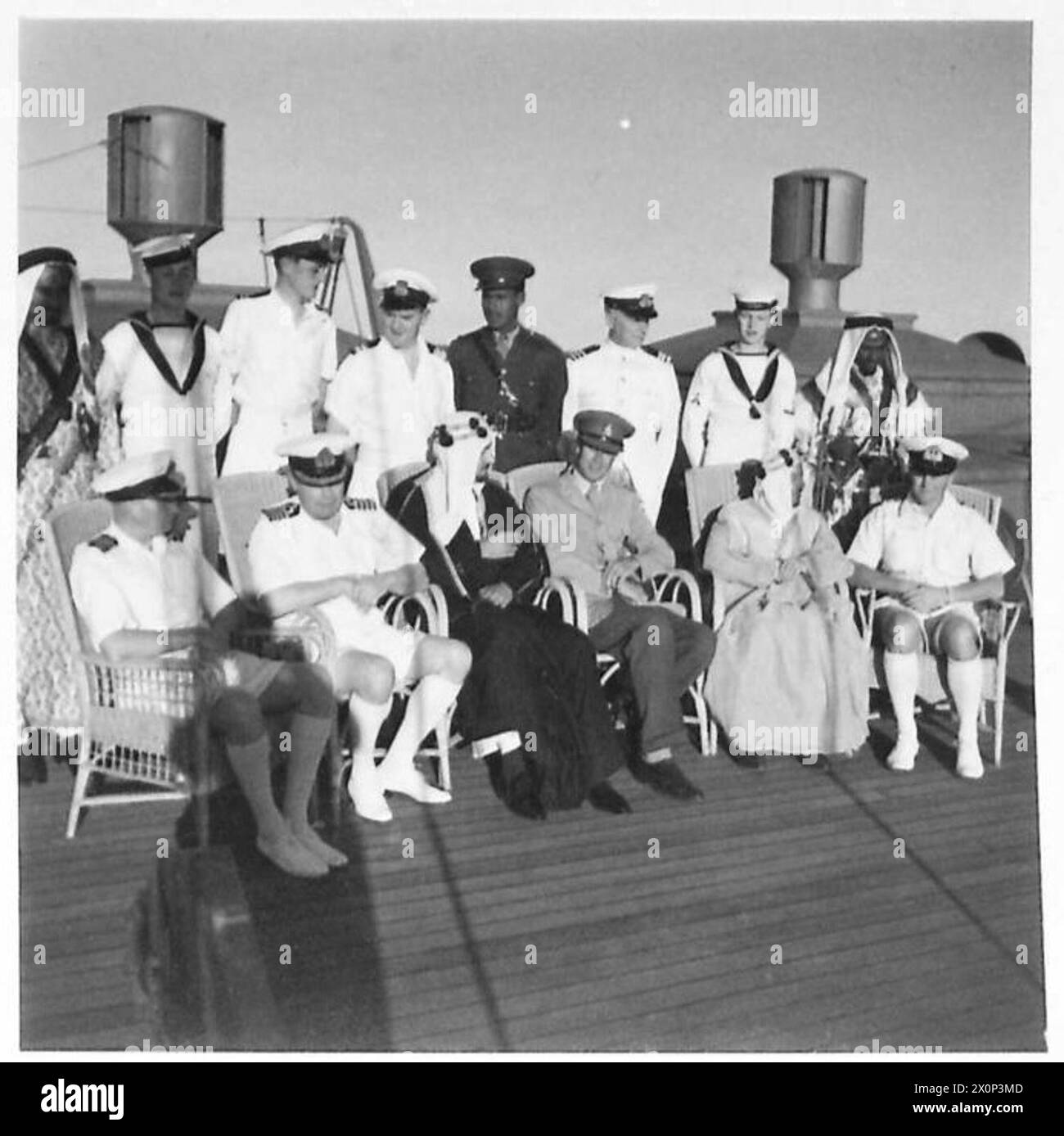 TOUR OF HRH EL EMIR MANSUR IBN SAUD - A group on deck. From left to right:-Back Row: A body-guard, A Naval Able Seaman, Lieutenant D A Holbrook NR, Purser W H Powers, Lieutenant M Diab Interpreter, Chief Engineer of the ship W Neilson, a Naval Able Seaman, a Body-guard.Front Row: Captain L C Barry RN, Captain C B Barry, DSO. RN, in charge of Naval Escort, His Royal Highness Emir Mansur bin 'Abd al-'Aziz, Captain P A Uniacke, acting as Liaison Officer, Dr Midhat Sheikh Al Ardh, Medical Adviser of HHR Emir Mansur bin 'Abd al'Aziz, Lieutenant Commander R M Marshall, RNVR Medical Officer Stock Photo